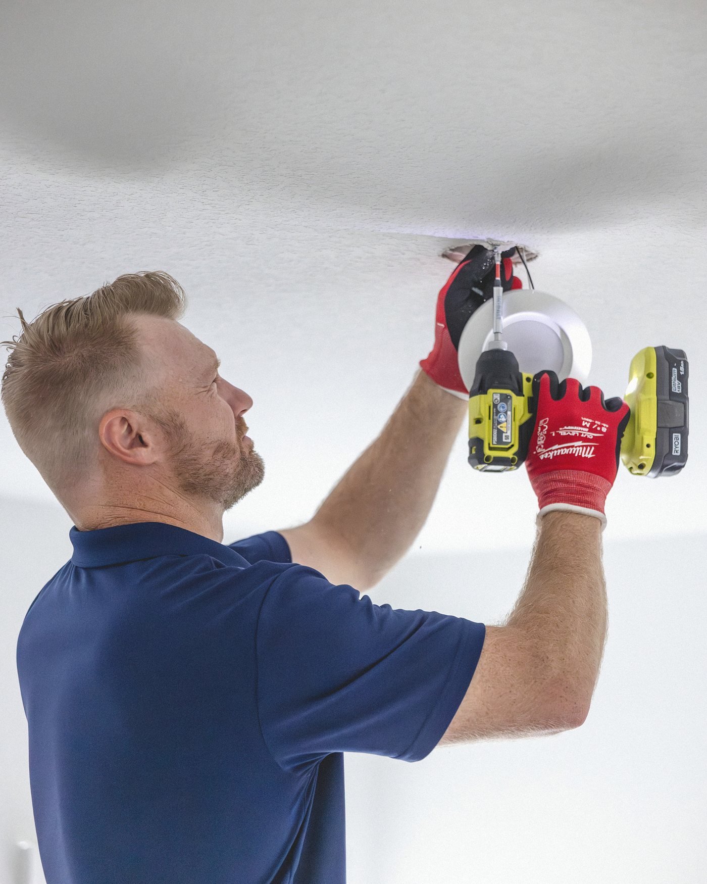 Warren driving a recessed can light into a ceiling with an impact driver