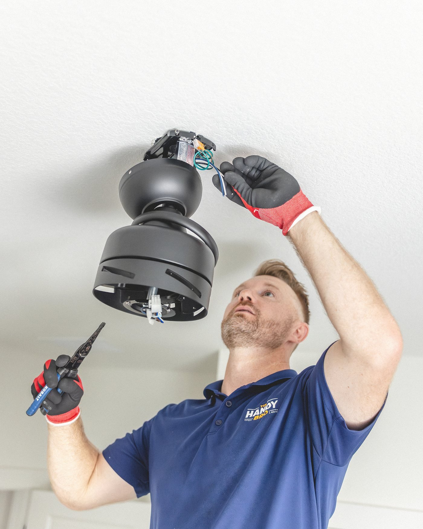 Warren wiring a ceiling fan motor at the junction box, pliers in hand