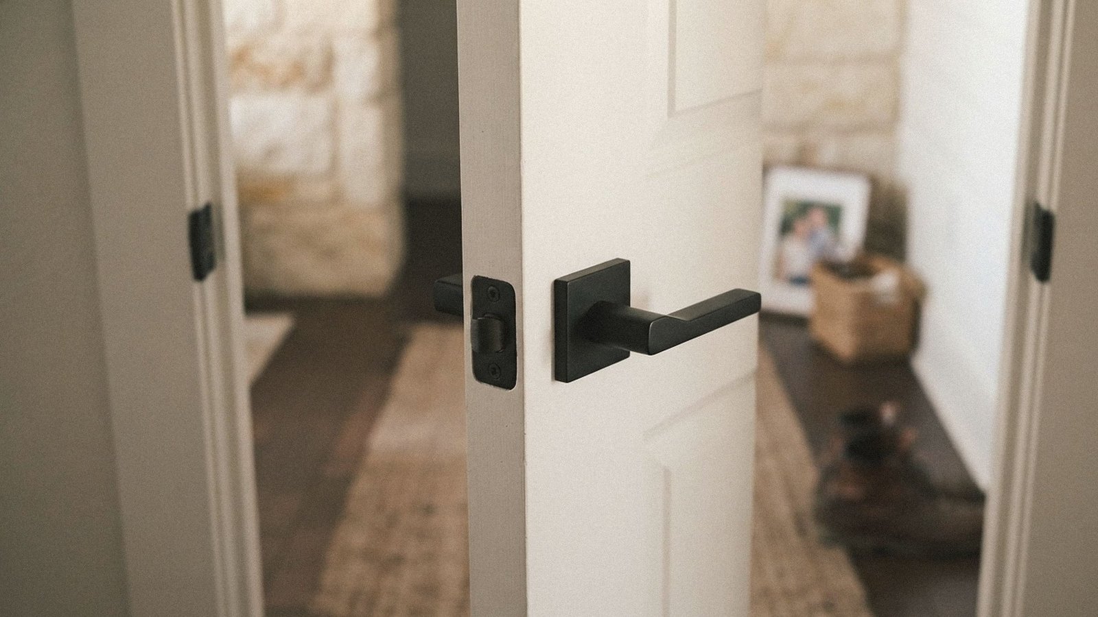 New matte black lever handle, strike plate, and hinge on a white shaker interior door